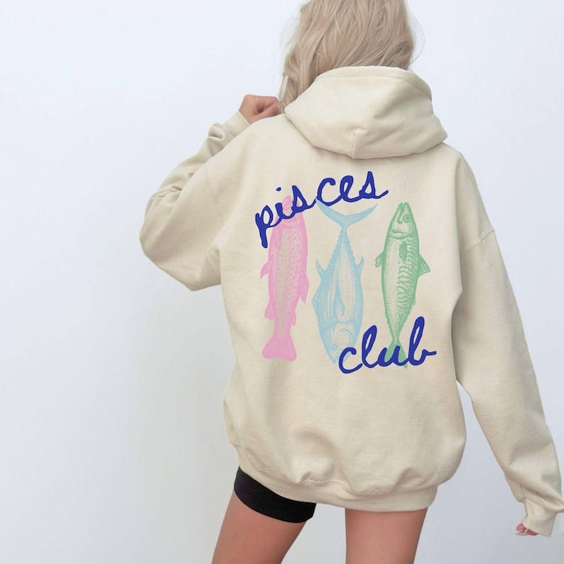 May include: A cream-colored hoodie with a blue graphic of three fish and the text "pisces club" on the back.