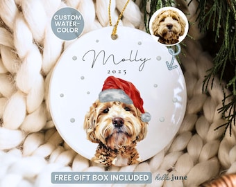 May include: A white ceramic Christmas ornament featuring a dog wearing a Santa hat. The ornament has the name "Molly" and the year "2025" written on it. The words "Custom Watercolor" are also visible. The ornament is round with a gold string for hanging.