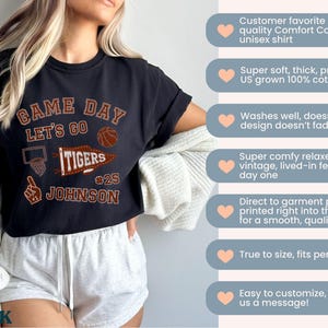May include: Black unisex t-shirt with "GAME DAY" and "LET'S GO TIGERS" text, a basketball graphic, and the name "JOHNSON" with the number 25. The shirt is made of soft, pre-shrunk cotton.