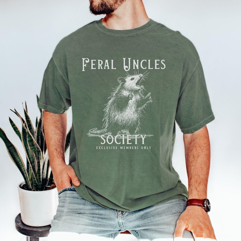 May include: A green t-shirt with a white graphic of a possum with the text "Feral Uncles Society Exclusive Members Only".