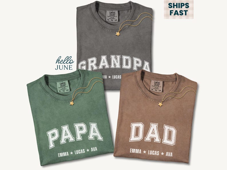 May include: Three t-shirts in gray, green, and brown, each with a different word in white block letters: "GRANDPA", "PAPA", and "DAD". Each shirt has a gold star necklace. The names Emma, Lucas, and Ava are printed below each word.