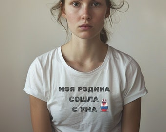 May include: A woman wearing a white t-shirt with the text "моя родина сошла с ума" and a Russian nesting doll graphic.