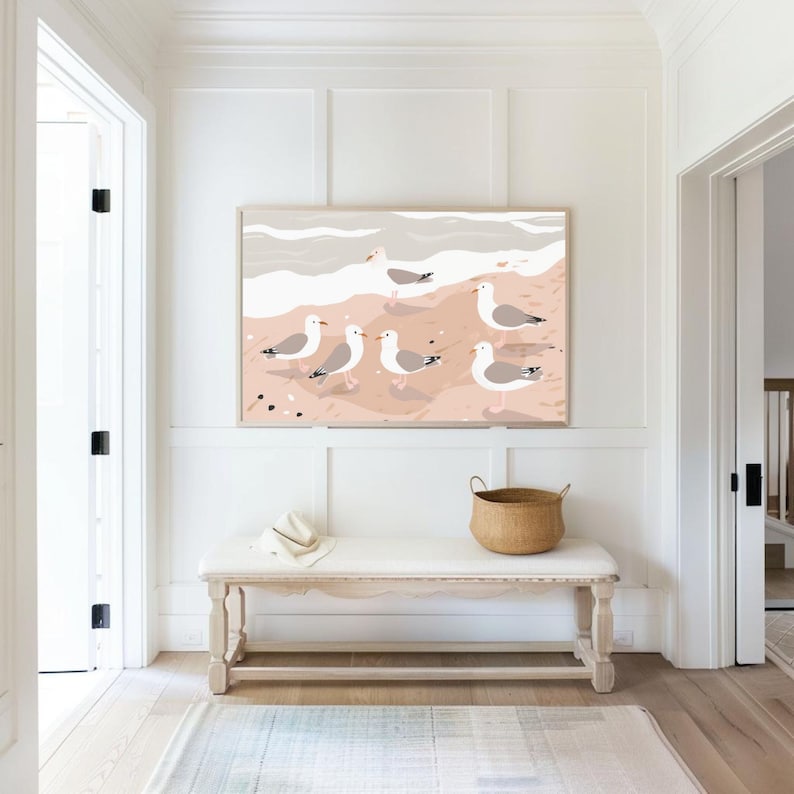 May include: A white wooden bench with a woven basket and a white hat on top. A framed print of seagulls on a beach hangs on the wall behind the bench.