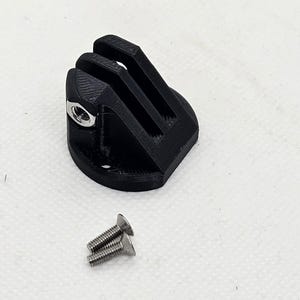 Op de afbeelding: Zwarte plastic camerabevestiging met drie sleuven en een schroefgat. Twee zilveren schroeven zijn inbegrepen.
