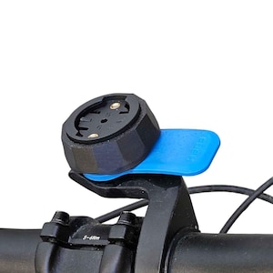 Peut inclure: Support de compteur de vélo noir avec une base bleue fixé sur le guidon. Le support est conçu pour maintenir un ordinateur de cyclisme. Le guidon est noir.