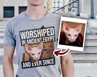 May include: A grey t-shirt with a black and white graphic of a hairless cat. The graphic says "Worshipped in Ancient Egypt and Ever Since".