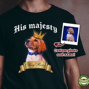 May include: Black t-shirt with a custom photo of a dog wearing a crown and a blue bow tie. The text "His majesty" is above the dog and "King Rocky" is below the dog. The text "Custom photo and name!" is in the bottom right corner of the image.