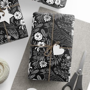 May include: Three black and white gift boxes with a floral and raven design. The boxes are wrapped with twine and have white paper tags attached.