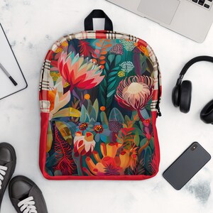 May include: A red backpack with a floral pattern featuring colourful flowers and leaves. The backpack has a black zipper and a plaid pattern on the top flap.