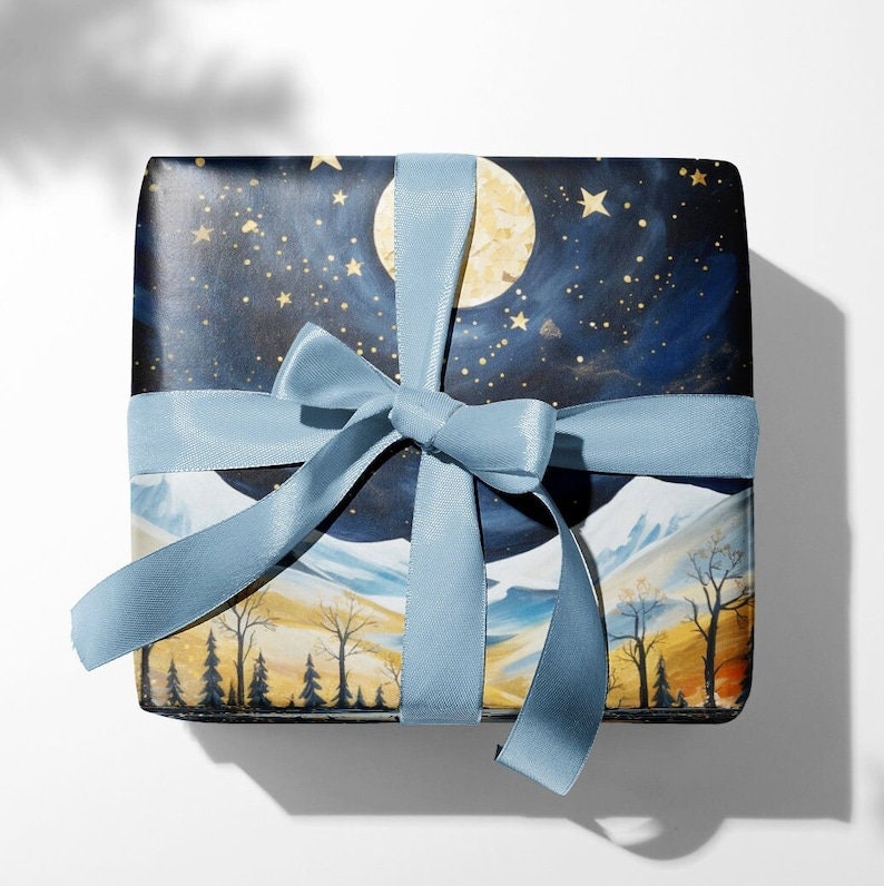 May include: A blue gift box with a white ribbon and a starry night sky design. The box features a large moon and a mountain range in the background.