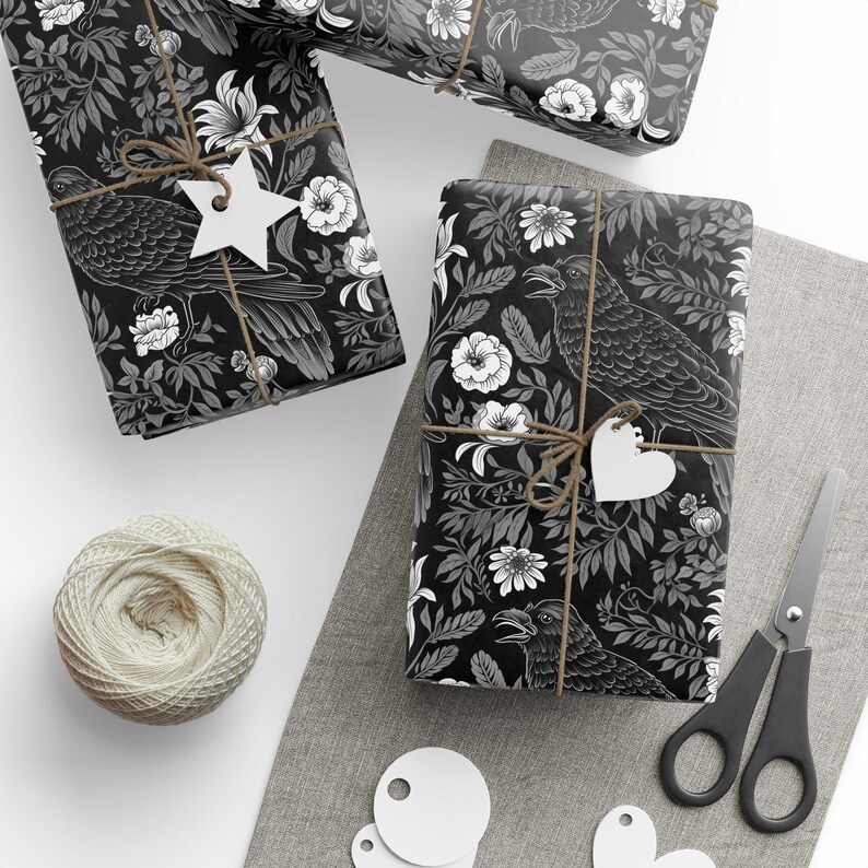 May include: Three black and white gift boxes with a floral and raven design. The boxes are wrapped with twine and have white paper tags attached.