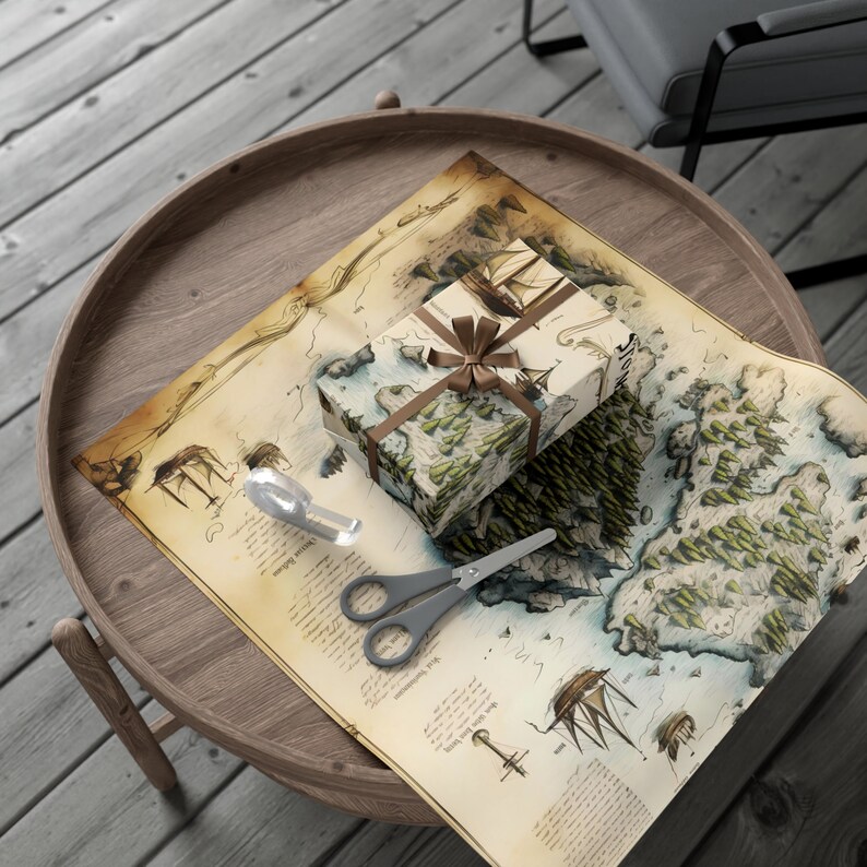 Puede incluir: Una caja de regalo marr&oacute;n envuelta en papel de mapa vintage con una cinta y un lazo marrones. La caja est&aacute; sobre una bandeja de madera con unas tijeras y un cortapapeles plateado.