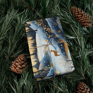May include: Blue and gold gift wrap featuring a winter forest scene with a deer. The paper is tied with twine and has a gold foil finish.