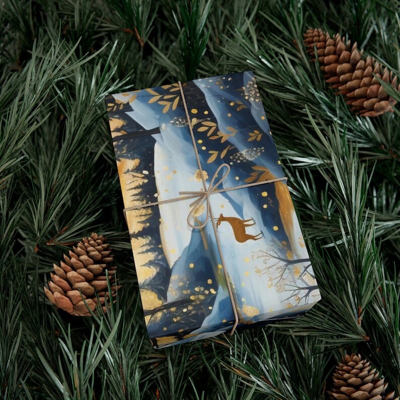 May include: Blue and gold gift wrap featuring a winter forest scene with a deer. The paper is tied with twine and has a gold foil finish.