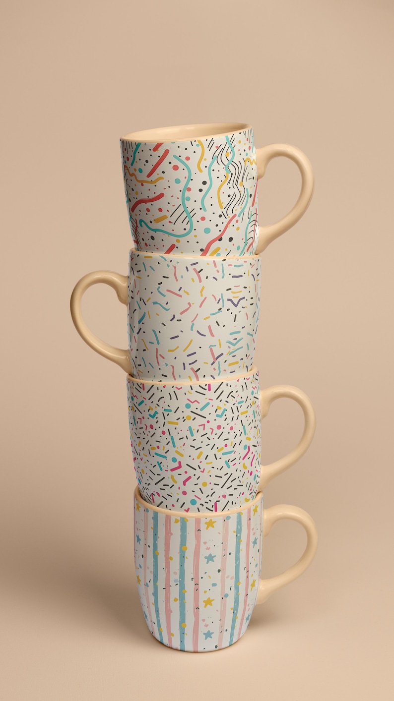 May include: A stack of four ceramic mugs with different colorful geometric patterns. The mugs are stacked on top of each other, with the top mug being a light blue and white striped mug with gold stars.