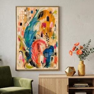 Può includere: Stampa artistica astratta in una cornice dorata. L'opera presenta un vivace mix di colori, tra cui blu, arancione, rosa e nero, con pennellate e forme geometriche. Il dipinto è appeso sopra un mobile in legno con una poltrona verde e un vaso di fiori.