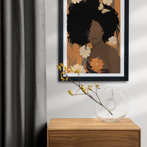 Pu&ograve; includere: Un'illustrazione incorniciata di una donna con la pelle marrone scuro e capelli neri ricci. Indossa un vestito a fantasia e ha una farfalla sui capelli. Lo sfondo &egrave; di colore arancione caldo con fiori gialli.