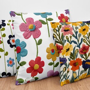 Pu&ograve; includere: Tre cuscini decorativi con motivi floreali. I cuscini sono bianchi con fiori ricamati colorati. Un cuscino ha un motivo floreale pi&ugrave; astratto con una variet&agrave; di colori.