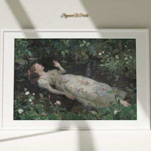 Può includere: Stampa artistica incorniciata raffigurante una donna in abito floreale che galleggia in un ruscello. L'opera d'arte è ambientata in un ambiente lussureggiante e verde con fiori bianchi e rosa. La stampa è in una cornice bianca.