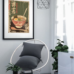 May include: A framed print of a vintage Japanese poster featuring a bowl of ramen noodles with a green background and the text "Ramen" in Japanese characters.