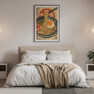 K&ouml;nnte beinhalten: Ein Schlafzimmer-Interieur mit einem wei&szlig;en Bett, einer braunen Wolldecke und zwei wei&szlig;en Nachttischen. Ein gerahmtes Poster einer Sch&uuml;ssel mit Ramen-Nudeln mit dem Text "快餐店" h&auml;ngt an der Wand &uuml;ber dem Bett.
