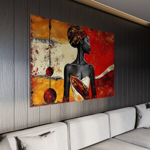 May include: Abstract painting of a woman with a red, yellow, and white background. The woman is wearing a white and red patterned dress and has a red head wrap. The painting is framed and hanging on a dark wood wall.