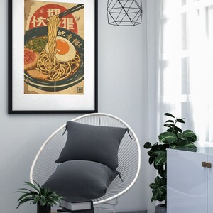 K&ouml;nnte beinhalten: Ein Vintage-Poster mit einer Sch&uuml;ssel Ramen-Nudeln mit einem Ei, Fr&uuml;hlingszwiebeln und Fleisch. Das Poster ist in Japanisch und sagt "Ramen" und "Lecker!"
