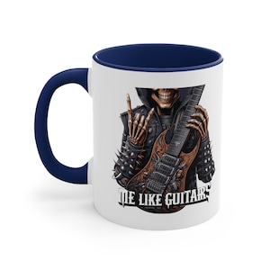 May include: White ceramic mug with a navy blue interior and handle. The mug features a graphic of a skeleton playing a guitar, wearing a studded leather jacket, and giving a rock and roll hand gesture. The text "ME LIKE GUITARS" is printed on the mug.