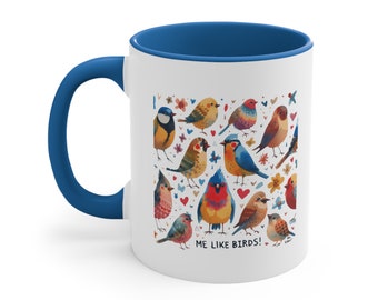 May include: White ceramic mug with a blue rim and handle. The mug features a colorful illustration of various birds with hearts and flowers. The text "ME LIKE BIRDS!" is printed on the bottom of the mug.