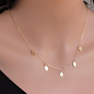 May include: A delicate gold necklace with a chain and four small leaf-shaped pendants.