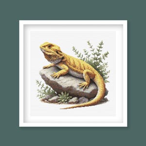 May include: A yellow bearded dragon lizard perched on a grey rock with green foliage in the background.