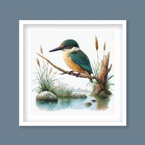 Sacred Kingfisher Kōtare Cross Stitch Pattern displayed in a green frame as native New Zealand bird wall art with wetland-inspired detail.