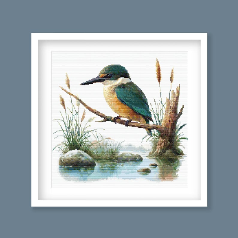Sacred Kingfisher Kōtare Cross Stitch Pattern displayed in a green frame as native New Zealand bird wall art with wetland-inspired detail.