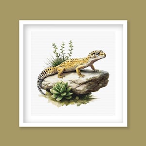 May include: A yellow and black leopard gecko lizard perched on a rock with green succulents and small plants.