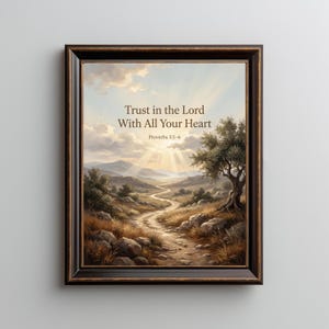 Peut inclure: Une impression d'art encadrée représentant un paysage avec un chemin de terre sinueux, un olivier et des montagnes sous un ciel ensoleillé. Le texte indique : Trust in the Lord With All Your Heart, Proverbs 3:5-6. Le cadre est brun foncé avec une bordure dorée.