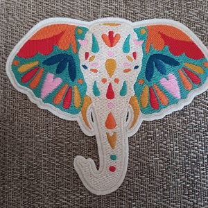 May include: A colorful embroidered elephant patch with a white background and intricate details in shades of orange, red, yellow, green, blue, and pink.