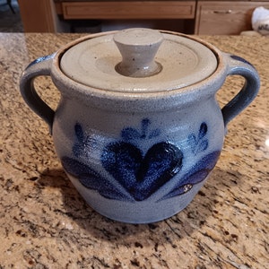 May include: A blue and white ceramic crock with a lid. The crock has a heart design and is decorated with blue flowers.
