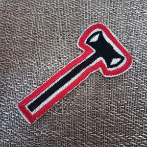 May include: A red and white embroidered patch shaped like a hammer with a black handle.