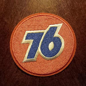 May include: A round, orange patch with a white outline of the number 76 in blue.