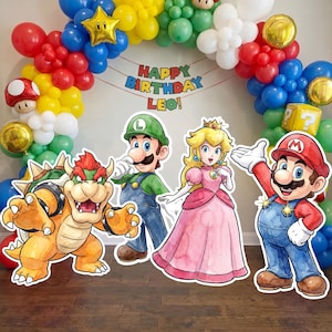 May include: A vibrant birthday party decoration featuring a balloon arch in red, blue, yellow, and green. Cardboard cutouts of Mario, Luigi, Princess Peach, and Bowser are in the foreground. The text "HAPPY BIRTHDAY LEO!" is visible.
