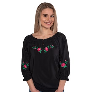 May include: Black embroidered blouse with pink and green floral designs. The blouse has a gathered neckline and 3/4 sleeves.