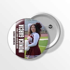 May include: A round button with a photo of a cheerleader in a maroon and white uniform. The button has the text "SENIOR 2025" and "MONICA GARCIA WASKOM WILDCATS VARSITY CHEER". The button is white with a metal pin back.