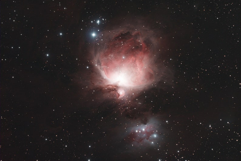 Puede incluir: Una imagen vibrante de la Nebulosa de Ori&oacute;n, una nube celestial de gas y polvo. La nebulosa presenta tonos rojos y rosas, con brillantes estrellas blancas dispersas sobre un fondo oscuro. Una vista impresionante del espacio profundo.