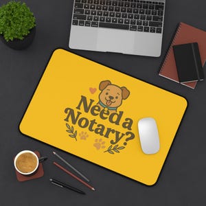May include: Yellow rectangular mousepad with the text "Need a Notary?" and a cartoon dog illustration. The mousepad has a black border and a white computer mouse is on the right side. A laptop, pens, and a coffee cup are also visible.