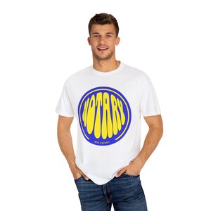 Puede incluir: Camiseta blanca con un círculo azul y la palabra "ROTARY" en letras amarillas dentro del círculo.