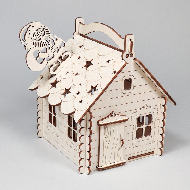 Pode incluir: Uma casa de Natal de madeira com uma figura do Pai Natal no telhado. A casa apresenta recortes em forma de estrela no telhado, janelas e uma porta. A casa &eacute; feita de madeira clara.