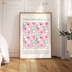 May include: A framed print with a floral design of pink roses and green leaves on a white backdrop. The text reads "PHILIPPIANS 4:13" at the top, with "I CAN DO ALL THINGS THROUGH CHRIST WHO STRENGTHENS ME" underneath. The frame is light brown.