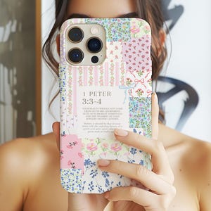 May include: A floral patchwork phone case with a light-colored background. The case features pink, blue, and white floral patterns, with the text "1 PETER 3:3-4" and a quote. The case is designed for a smartphone.