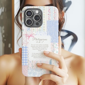 May include: A patchwork-style phone case with a floral and gingham pattern in pastel colors. The case features a quote from Philippians 4:6-7. The design includes pink, blue, and white elements, creating a soft, feminine aesthetic.