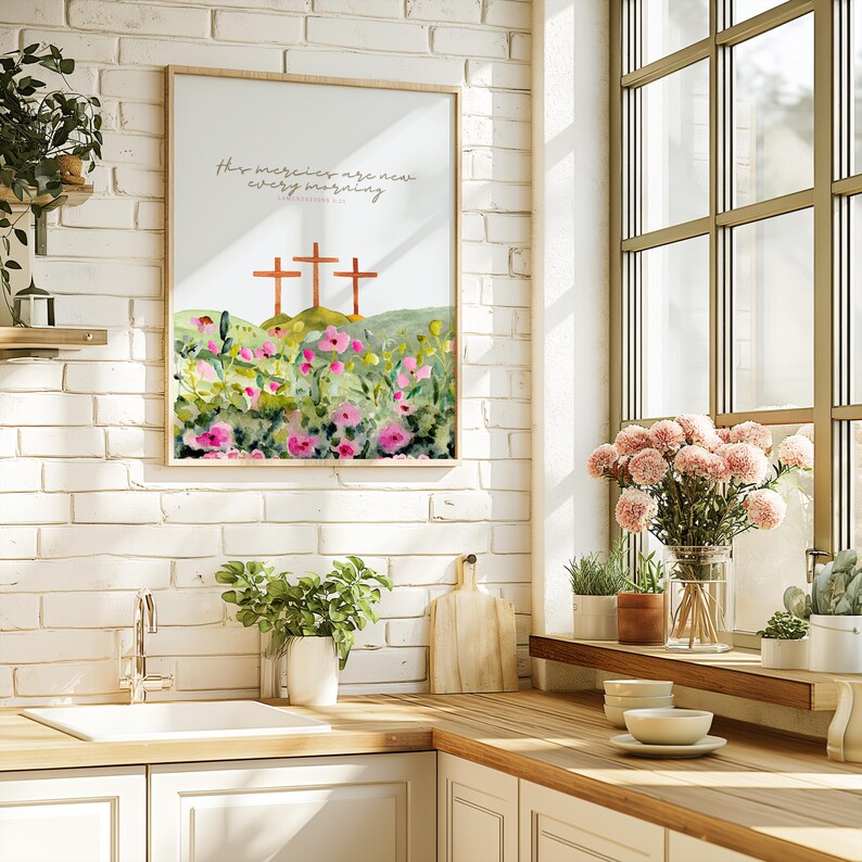 Pu&ograve; includere: Una stampa ad acquerello incorniciata con tre croci in cima a una collina verde, con un campo di fiori rosa e verdi in primo piano. Il testo "His mercies are new every morning" &egrave; scritto in alto.